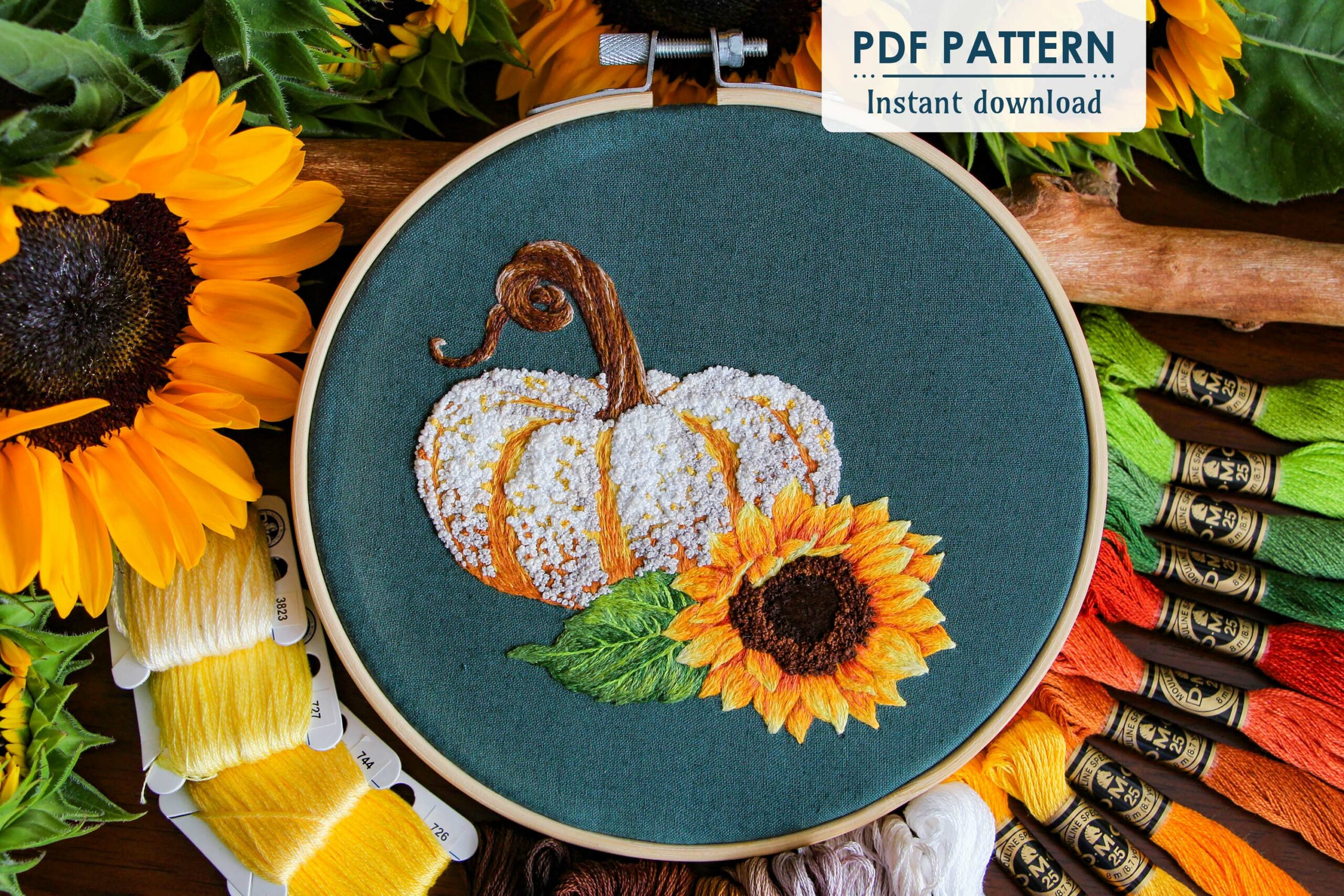 The finished hoop of the Autumn Spice Pumpkin embroidery features the thread painted pumpkin and sunflower. Surrounded by DMC thread colors and real sunflowers
